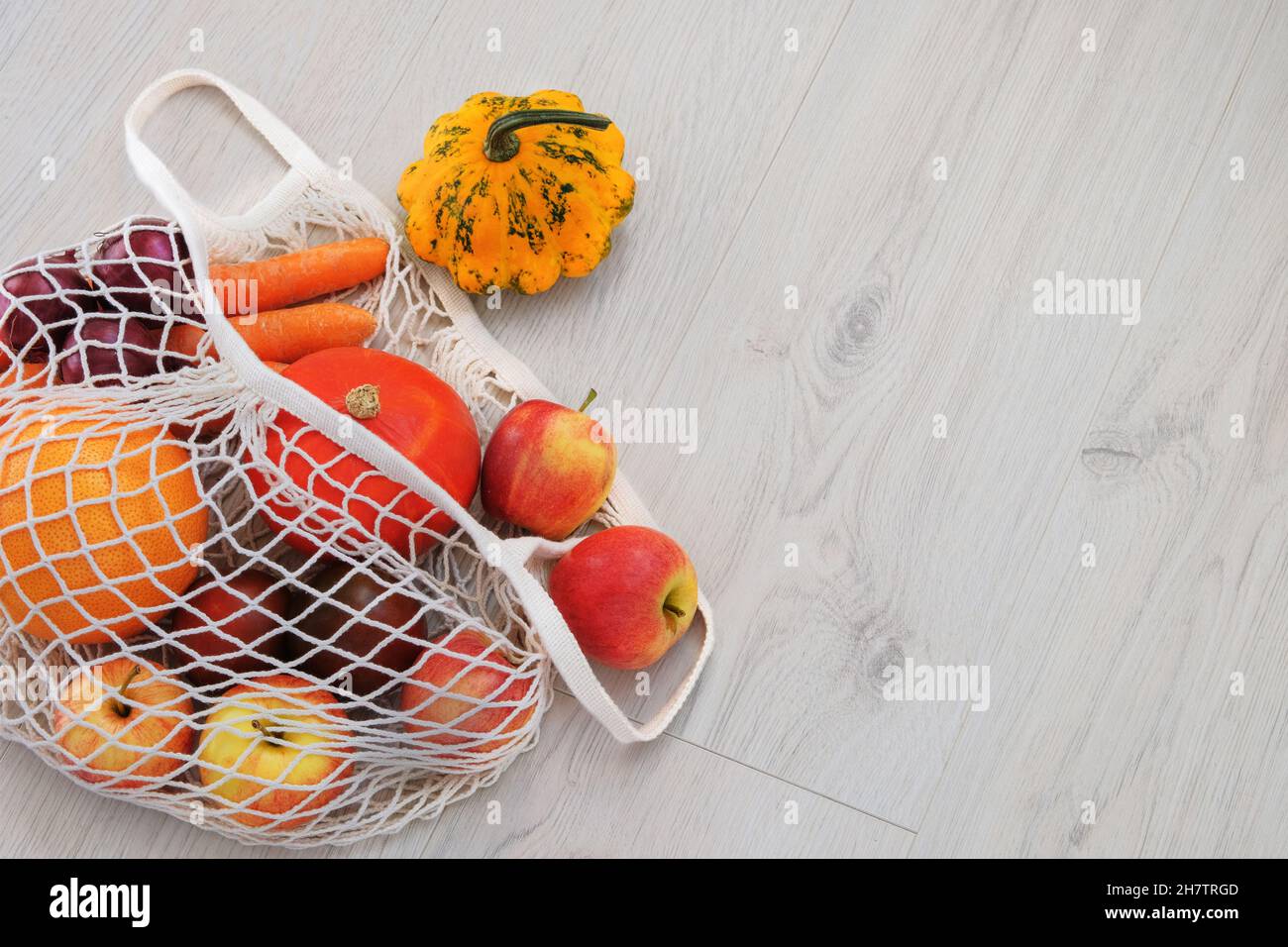 Borsa ecologica e verdure arancioni. Sfondo di cibo sano. Disposizione piatta. Stile di vita sostenibile. Cura dell'ambiente e rifiuto della plastica conce Foto Stock