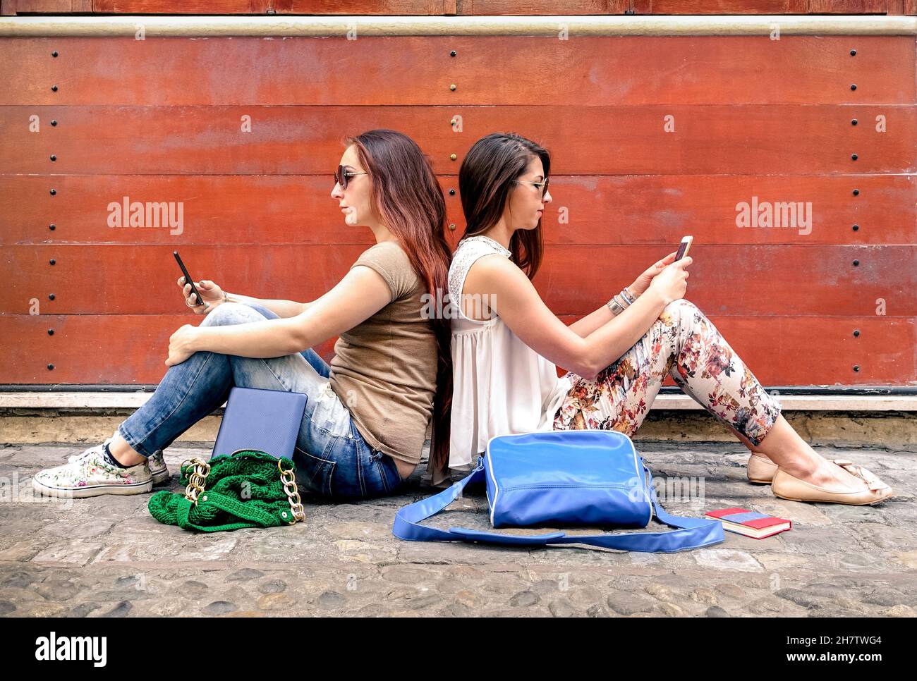 Hipster coppia di girlfriends in disinteresse momento con cellulari smart phone - concetto di relazione apatia tristezza e isolamento Foto Stock