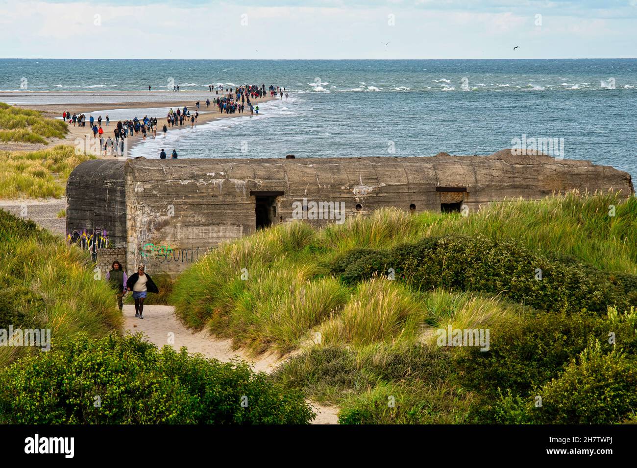 I turisti lungo la penisola sabbiosa di Grenen dove il Mar Baltico incontra il Mare del Nord. In primo piano le rovine del bunker. Frederikshavn, Danimarca Foto Stock