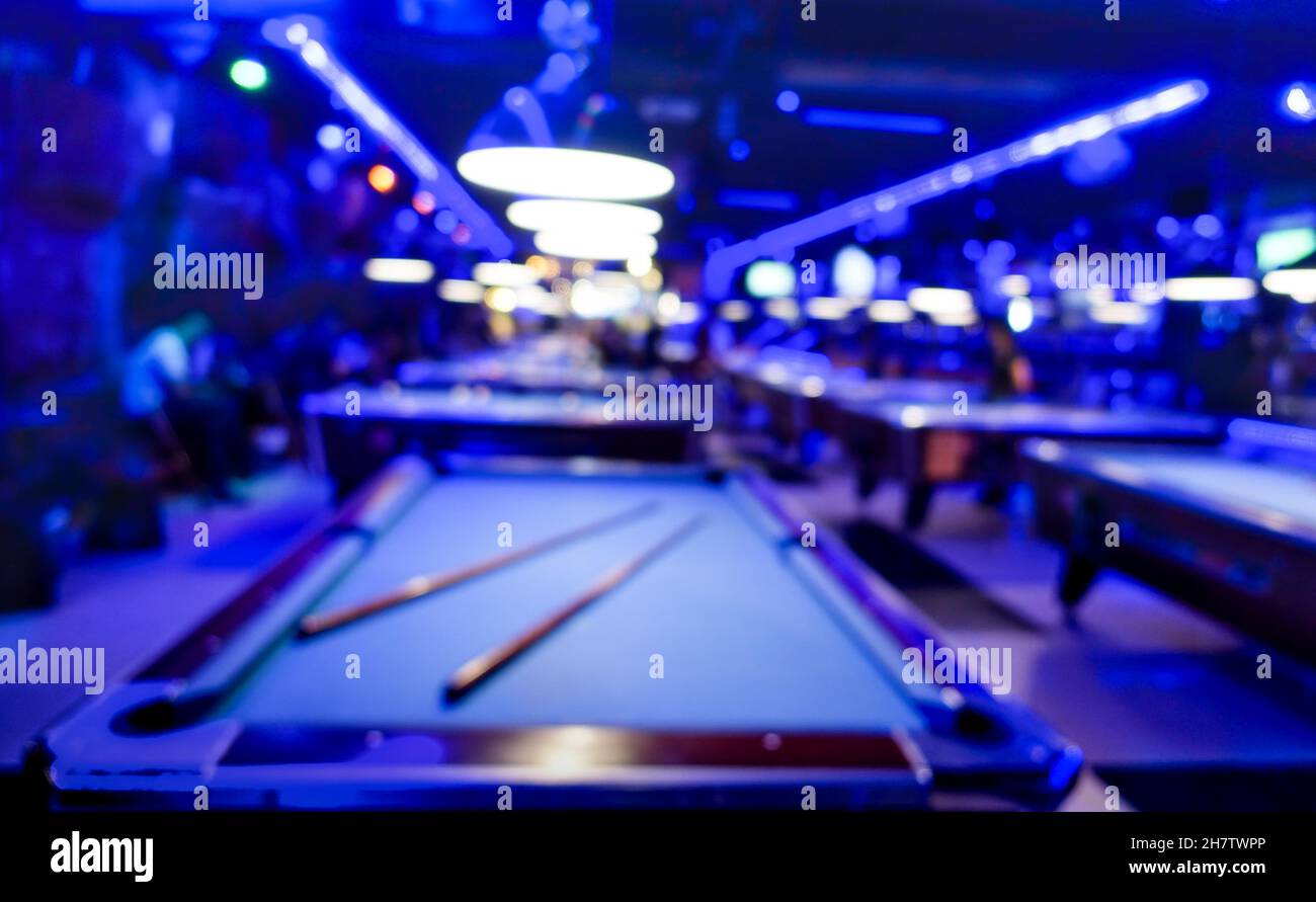 Sfondo sfocato della sala giochi biliardo - composizione sfocata del salone del gioco in piscina con toni di colore blu dominante e luce al neon incandescente Foto Stock