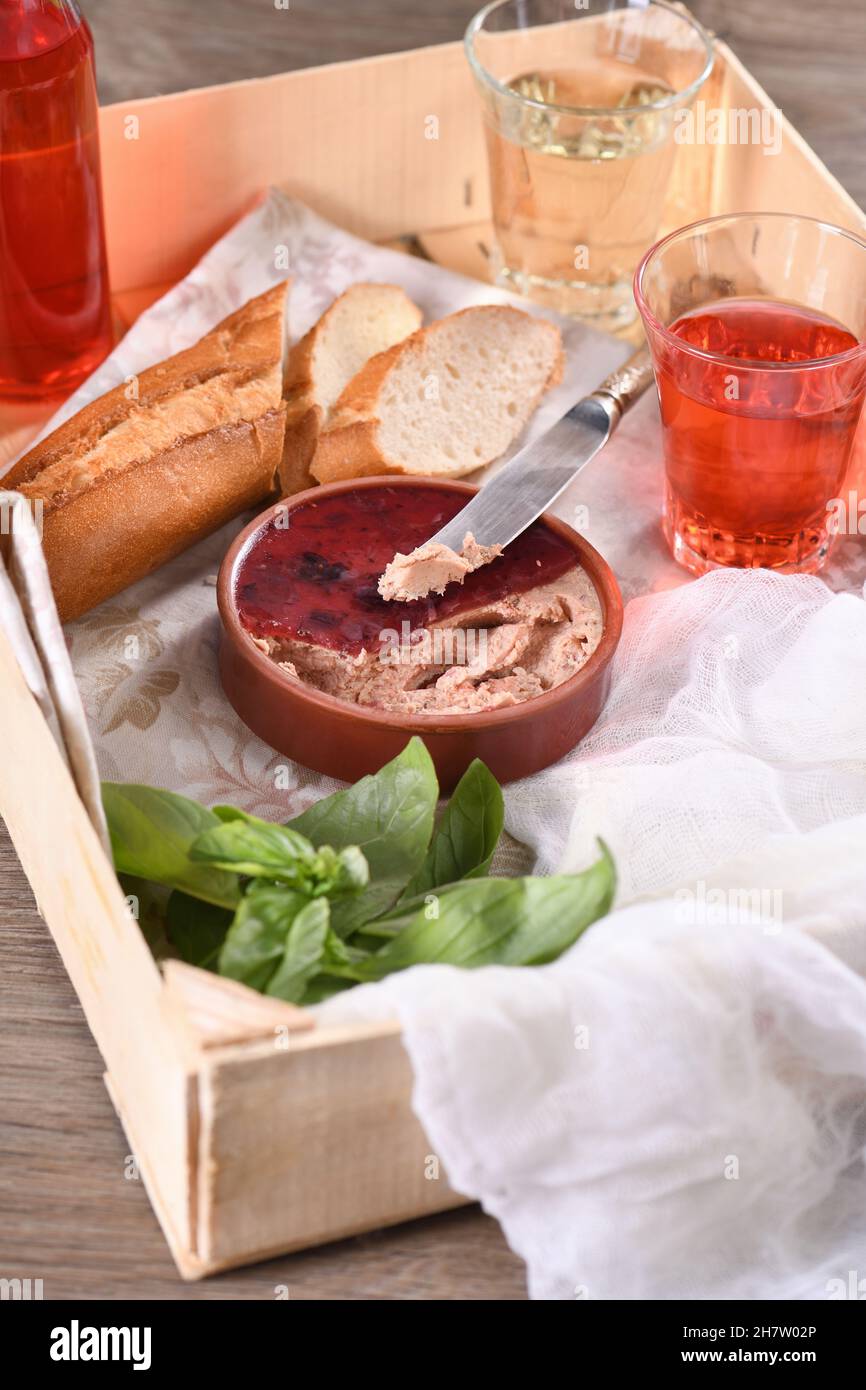 Delicato pato di pollo con mirtilli rossi purei, bevuto in gelatina. Servito con pezzi di baguette e bevanda alla frutta, in una scatola di legno. Cibo di stile country. Foto Stock