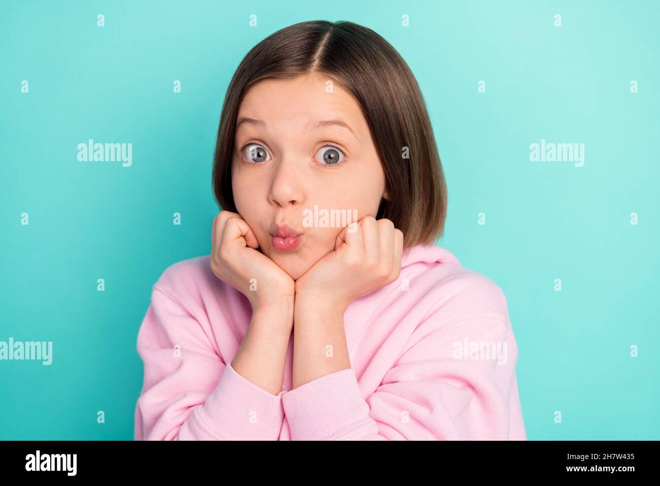 Foto di breve hairdo cute little girl le guance soffio bacio indossare sportivo rosa isolato su sfondo di colore teal Foto Stock