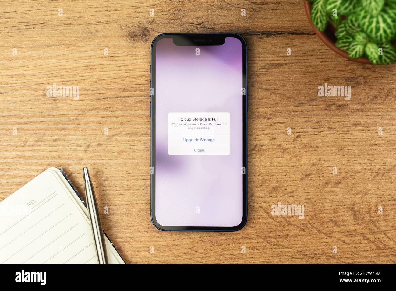 Kharkov, Ucraina - 21 novembre 2021: ICloud Storage è a schermo intero su Apple iPhone. Sfondo tavola in legno Foto Stock