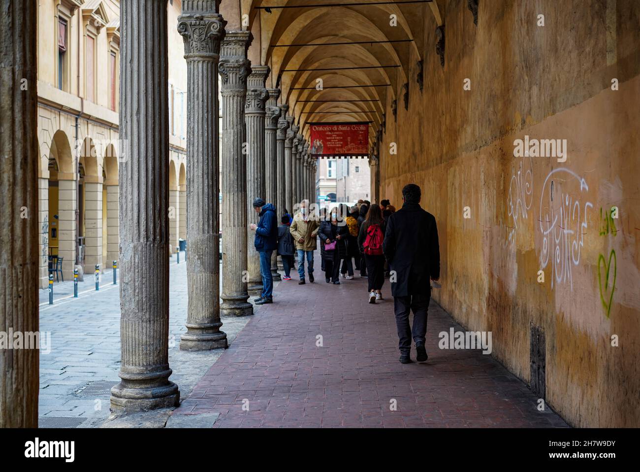 La gente cammina attraverso una galleria nella città italiana di Bologna. Foto Stock