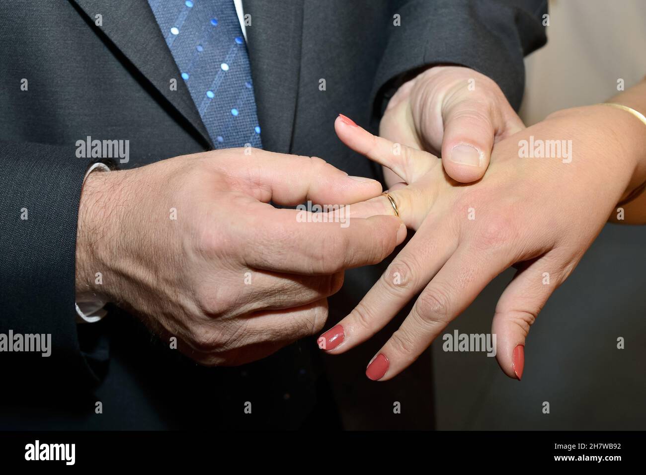Anello d'oro che lo sposo mette sul dito della sposa sul suo giorno di nozze. Foto Stock