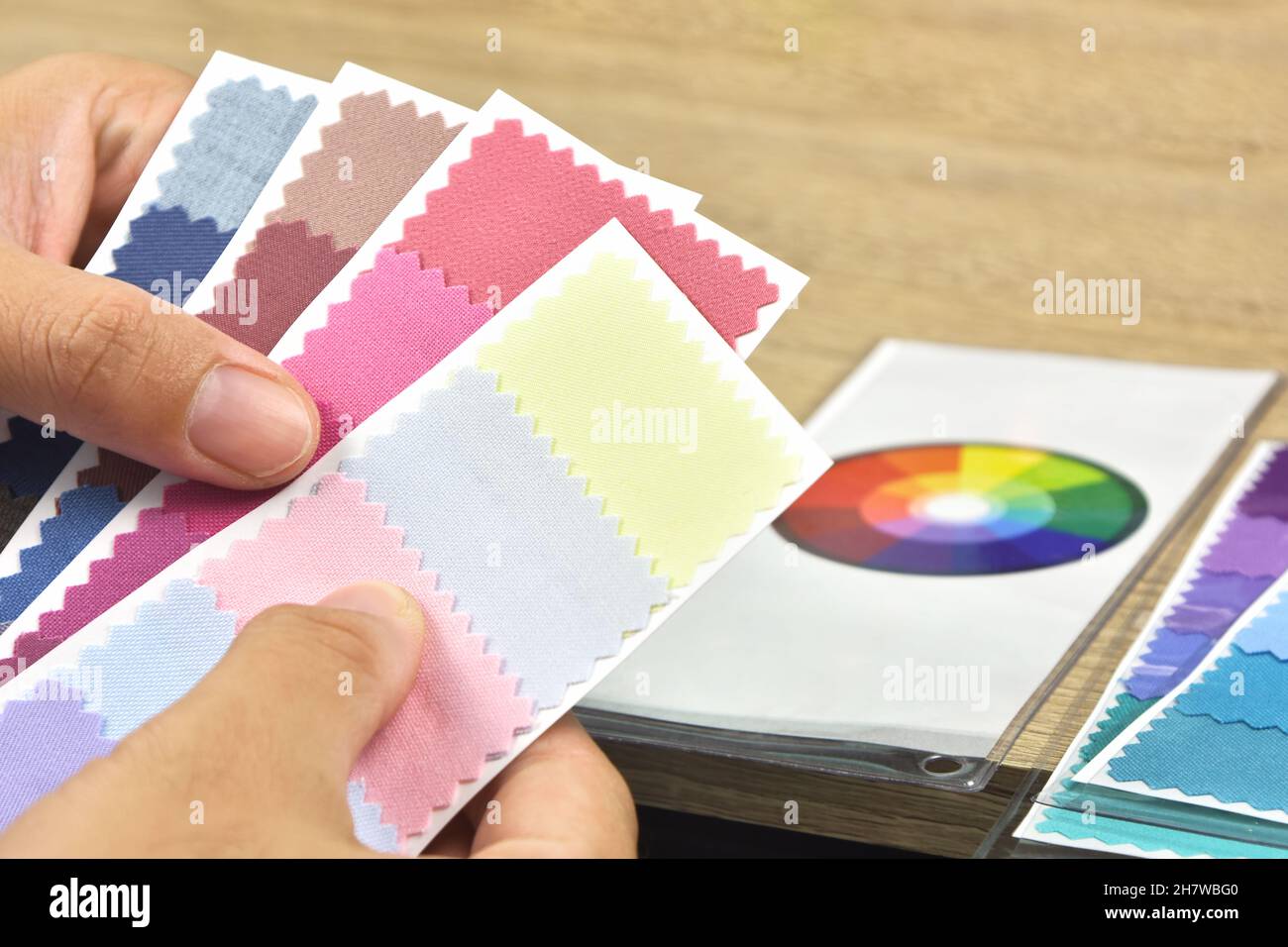 Il designer confronta le carte dei colori tessili sul tavolo in legno Foto Stock