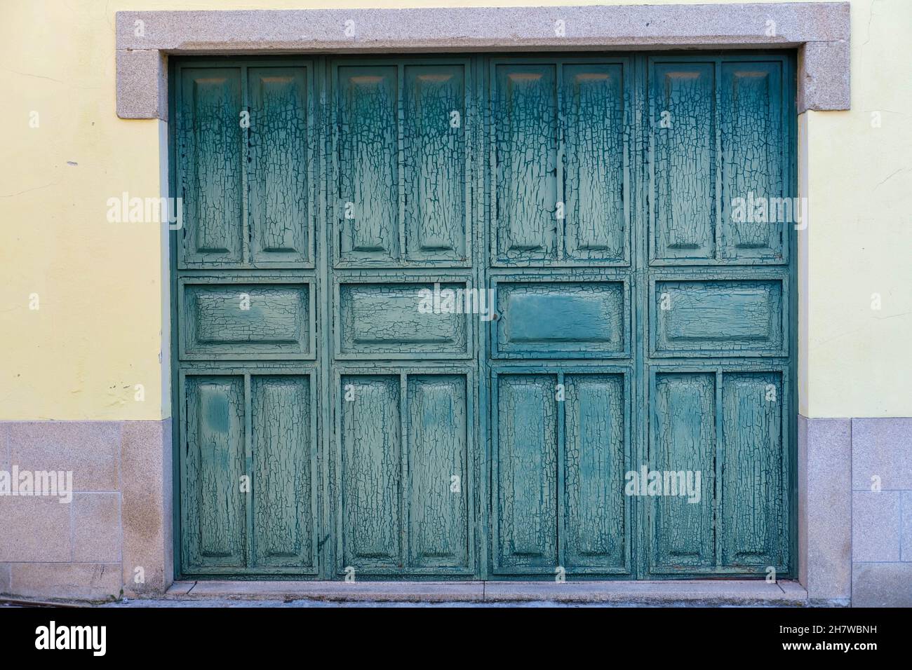 Porte doppie in legno da garage spaccate e spellate in verde Foto Stock