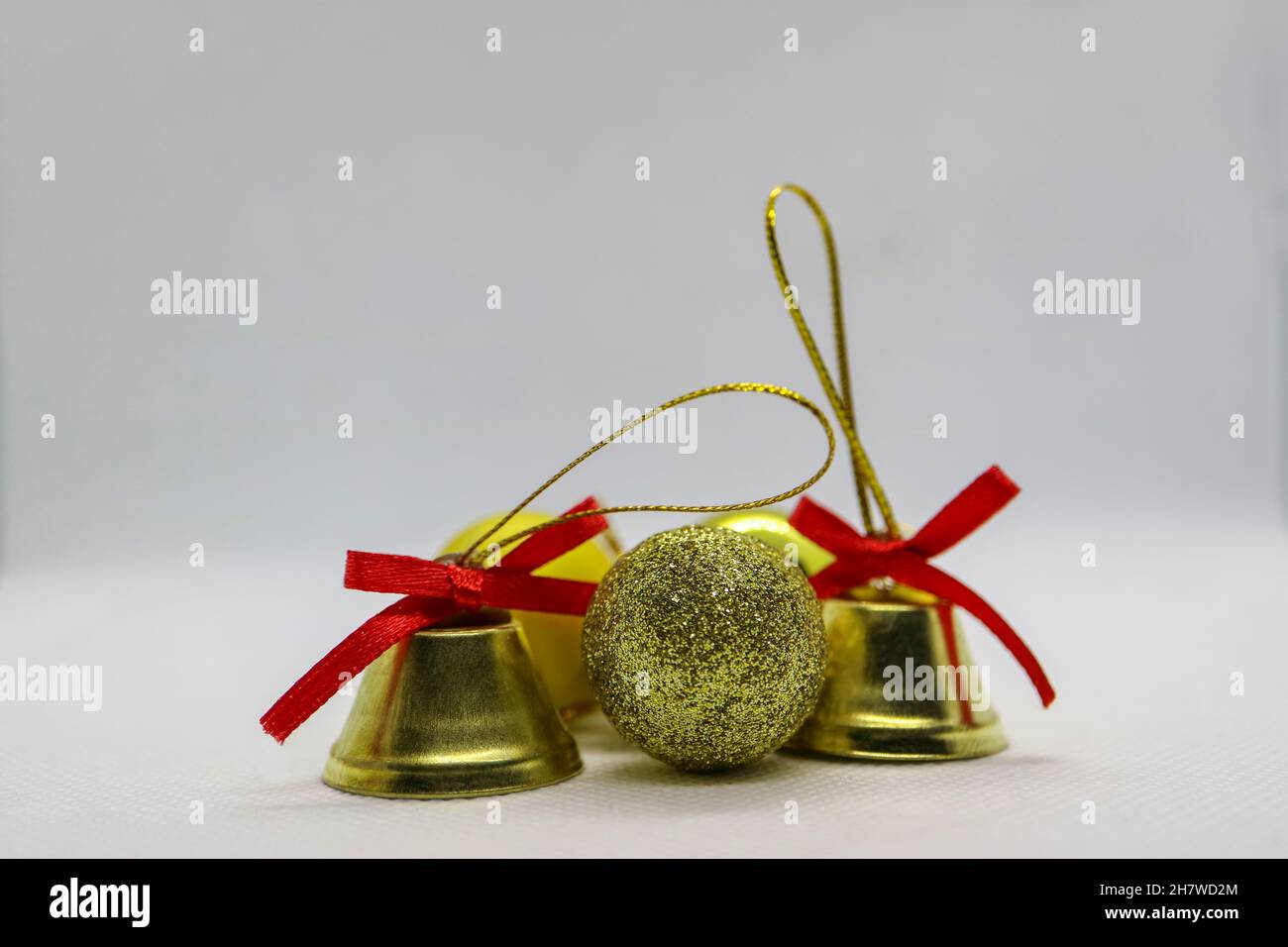 Campane e palle color oro, campane con archi rossi, decorazione natalizia su sfondo bianco, decorazione di Capodanno, biglietto di auguri per le feste, Foto Stock