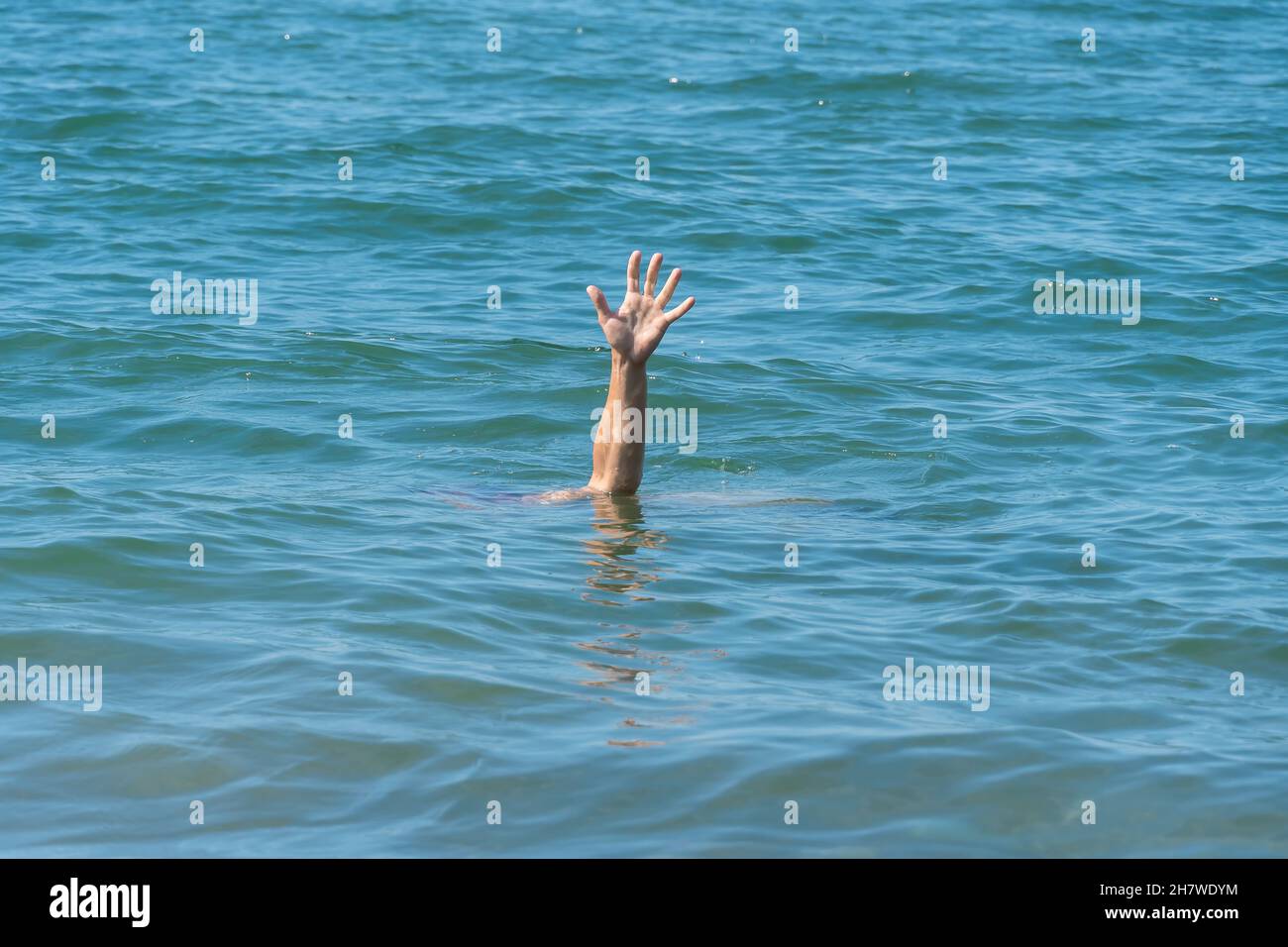 Una mano di un uomo annegante in mare, chiedendo aiuto in una giornata di sole Foto Stock