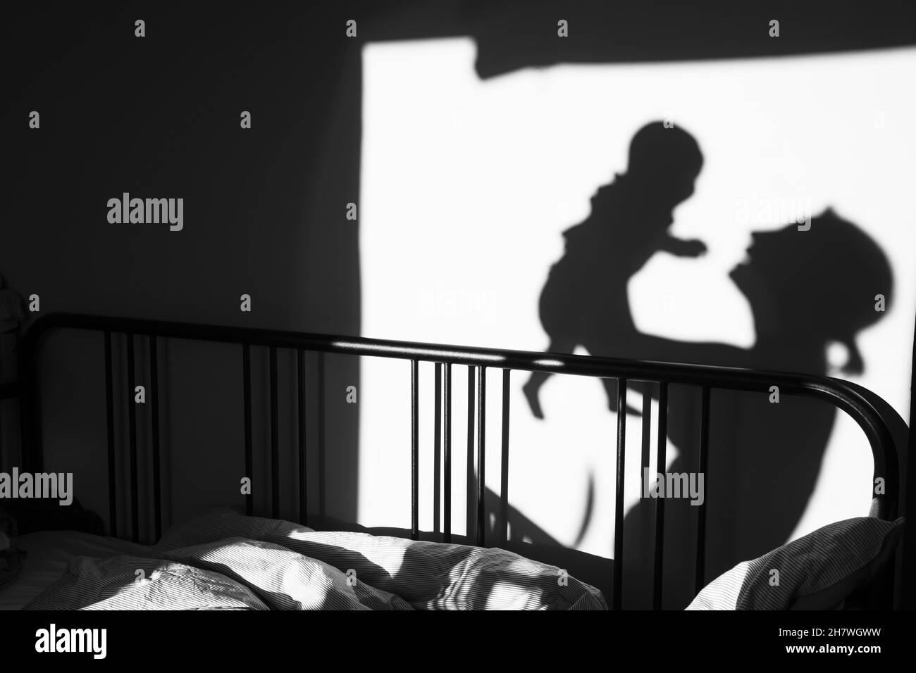 silhouette di un bambino e di un genitore che giocano nella stanza al mattino. Foto Stock