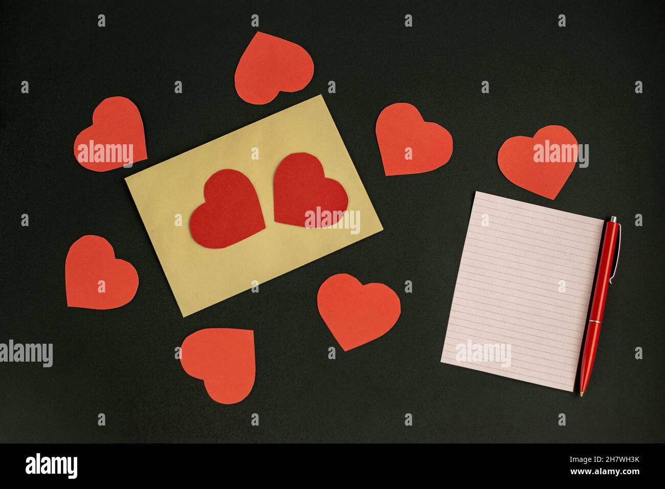 Lettera con una dichiarazione d'amore per San Valentino in una busta artigianale con cuori su sfondo scuro. Foto Stock
