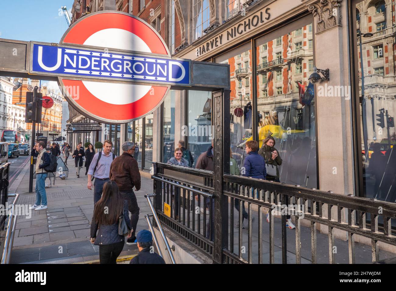 Negozi del West End. Gli amanti dello shopping nel quartiere dello shopping di Kensington a Londra, con l'iconica insegna della metropolitana di Londra e il negozio Harvey Nichols visibile. Foto Stock