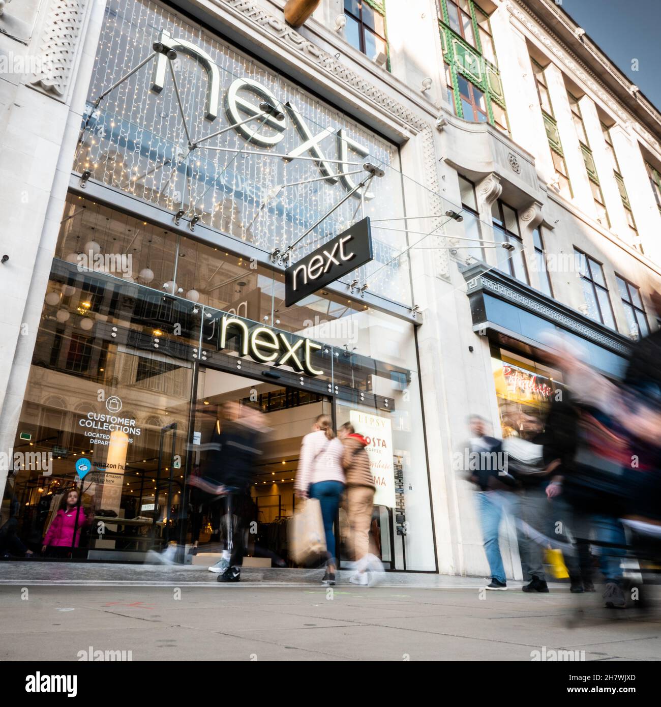 Vicino al negozio, Oxford Street, Londra. Gli amanti dello shopping passano l'entrata al popolare negozio di alta moda nel trafficato quartiere dello shopping di Londra. Foto Stock