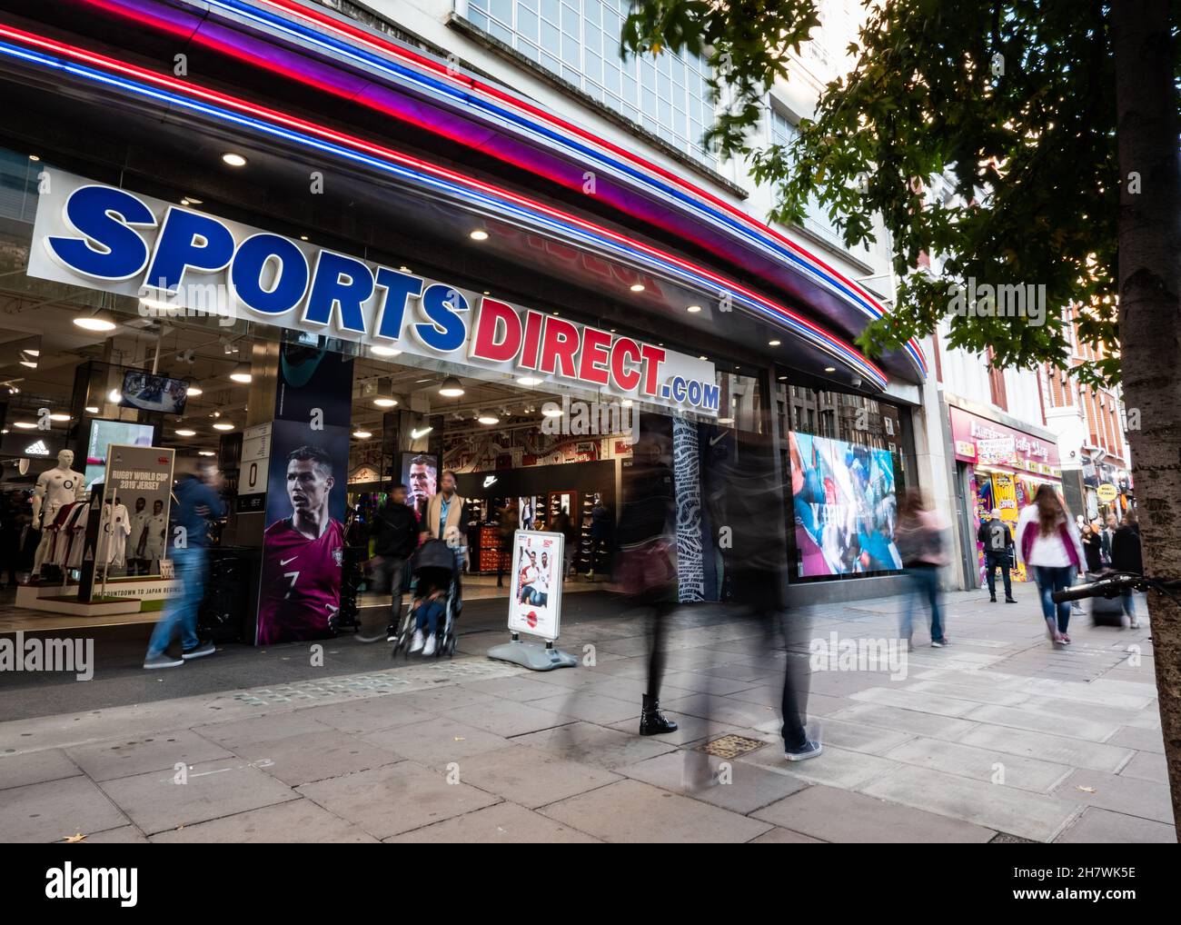 Negozio Sports Direct, Oxford St., Londra. Gli amanti dello shopping passano l'ingresso al negozio della catena sportiva di punta nel trafficato quartiere dello shopping di Londra. Foto Stock