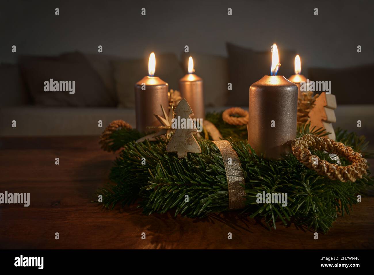 Candele d'oro su una corona d'avvento con alcune decorazioni natalizie naturali su un tavolo da caffè in legno nel soggiorno, spazio copia, fuoco selezionato, nar Foto Stock