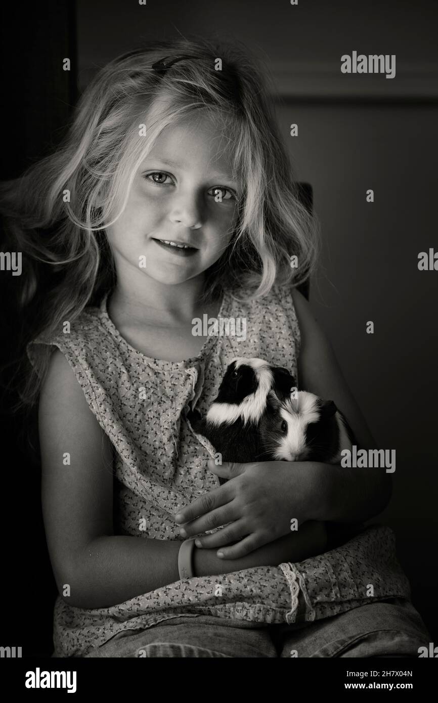 Una dolce bambina bionda dai 5 ai 6 anni con i suoi maiali Guinea Foto Stock