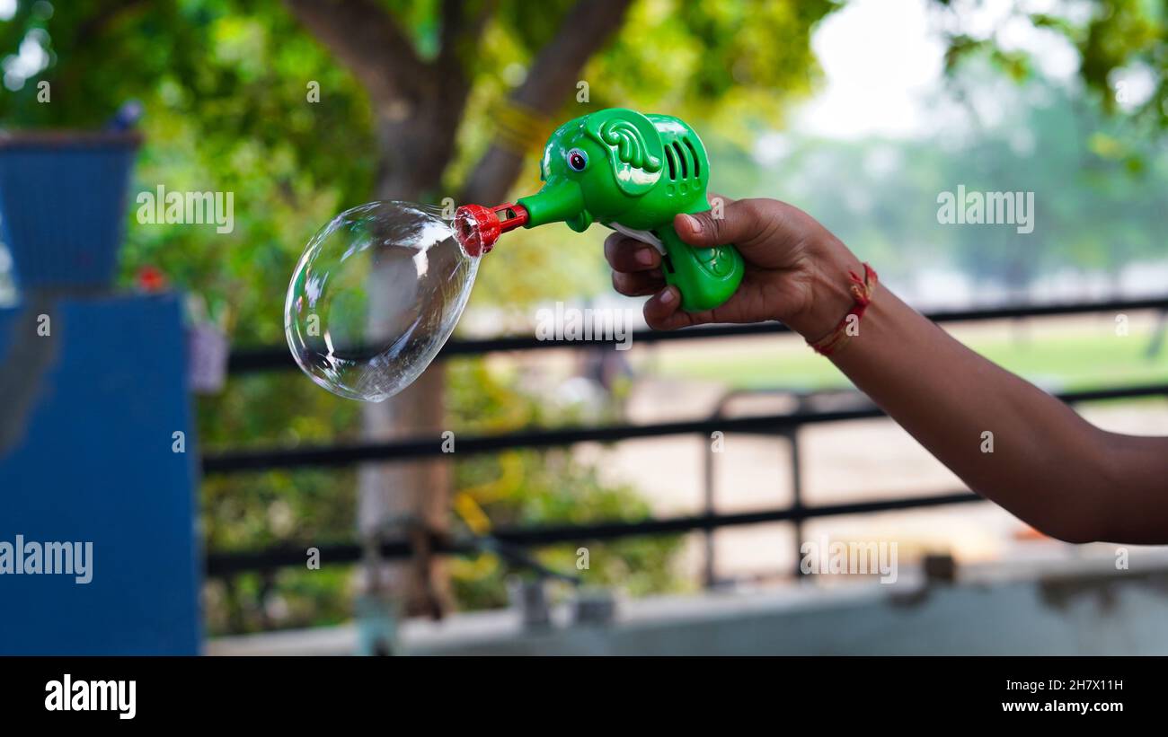 Ritratto di un soffiatore di bolla di sapone in una mano non identificata dei bambini. Bambini con soffiante a bolla. Foto Stock