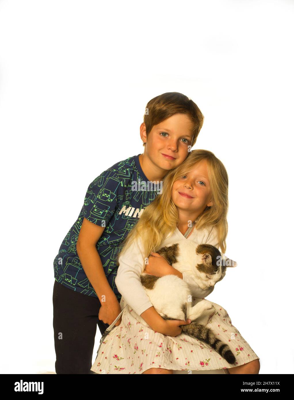 Un fratello e una sorella che tengono il loro gatto animale domestico Foto Stock