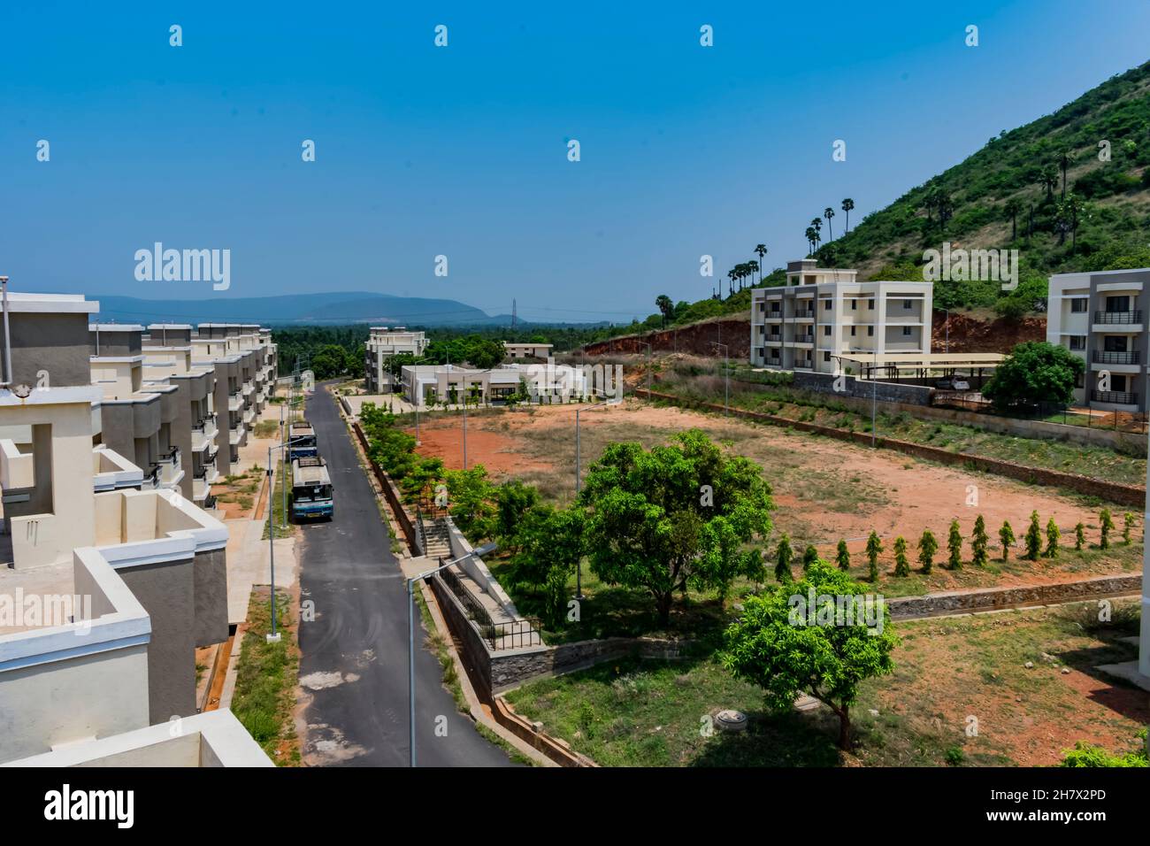 Vista dall'alto di una colonia indiana con strada bituminosa, edificio che guarda in linea con il modello, piccolo parcheggio, parco giochi che guarda impressionante dalla cima di un edificio Foto Stock