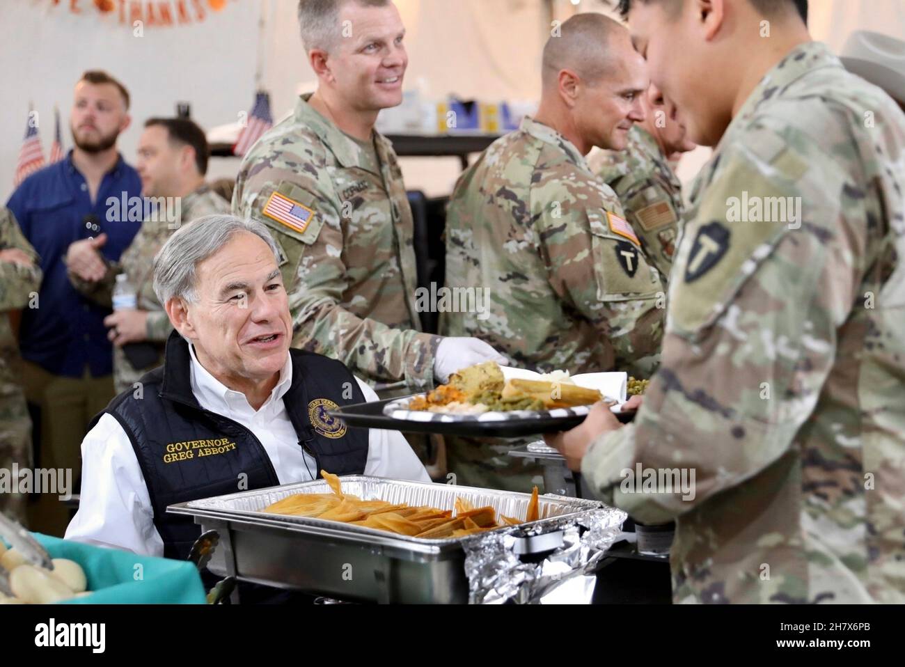 Del Rio, Stati Uniti. 24 novembre 2021. Texas Gov. Greg Abbott, a sinistra, aiuta a servire un pasto del primo giorno del Ringraziamento durante una visita con i membri del Dipartimento militare del Texas e del Dipartimento di pubblica sicurezza del Texas 24 novembre 2021 a del Rio, Texas. Credit: Capt. Phil Fountain/DOD/Alamy Live News Foto Stock