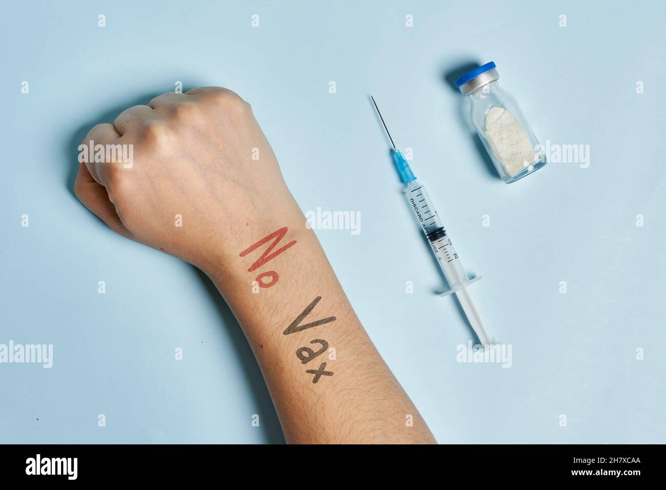 Antivaxer mano vicino alla siringa con vaccino Covid-19. Una persona che rifiuta l'immunizzazione contro il coronavirus. Concetto di scetticismo del Covid Foto Stock