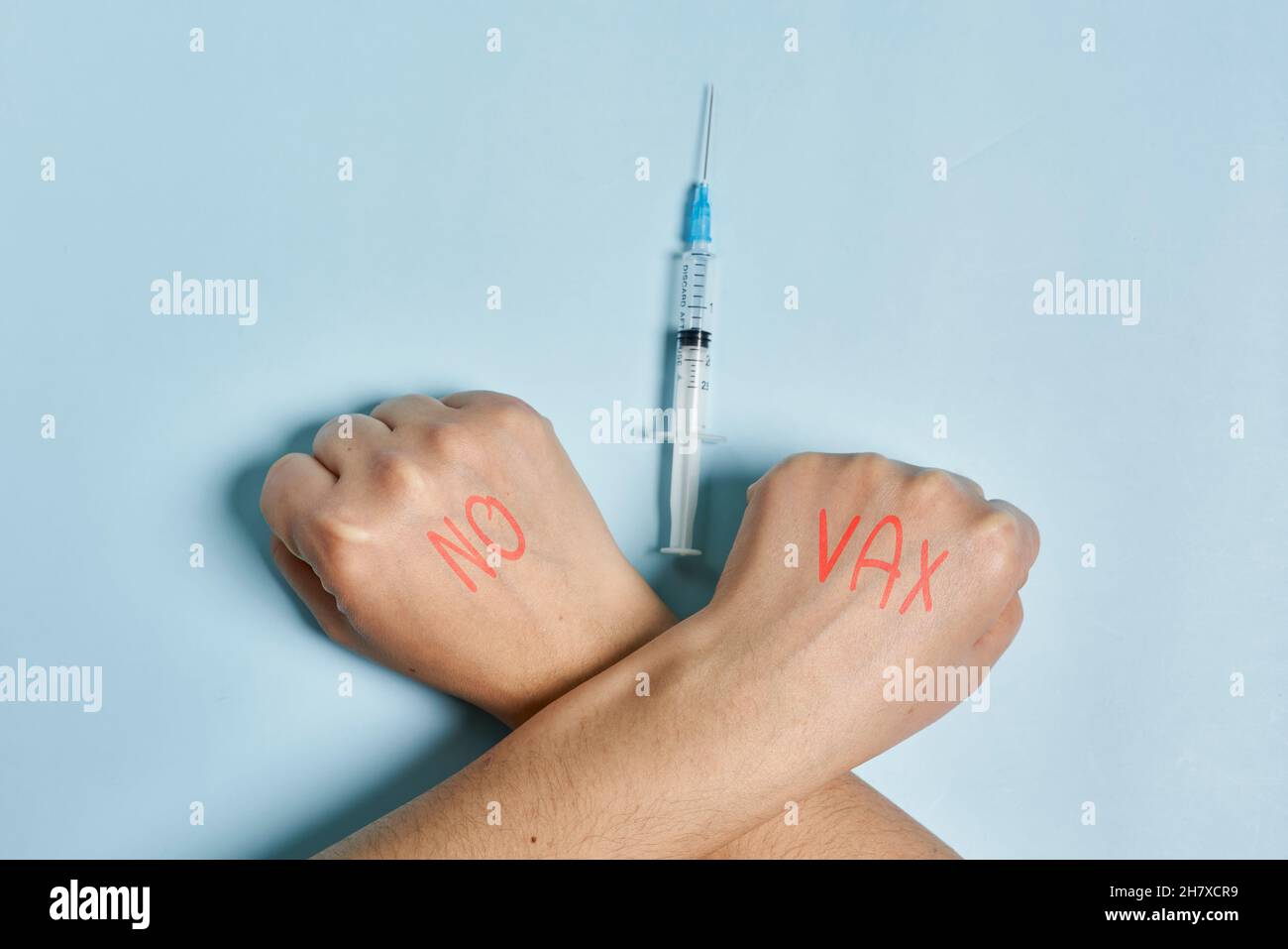 Antivaxer incrocia le mani vicino alla siringa con il vaccino Covid-19. Una persona che rifiuta l'immunizzazione contro il coronavirus. Concetto di scetticismo del Covid Foto Stock