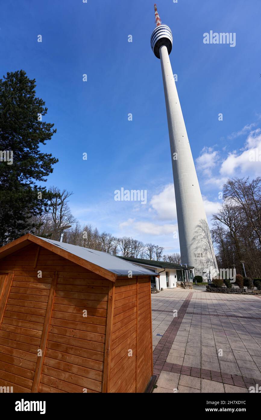 Stoccarda, Germania - 20 marzo 2021: Torre televisiva (Fernsehturm) su un quadrato con lastre di pietra. Piccola capanna marrone in primo piano. Cielo blu nel dorso Foto Stock