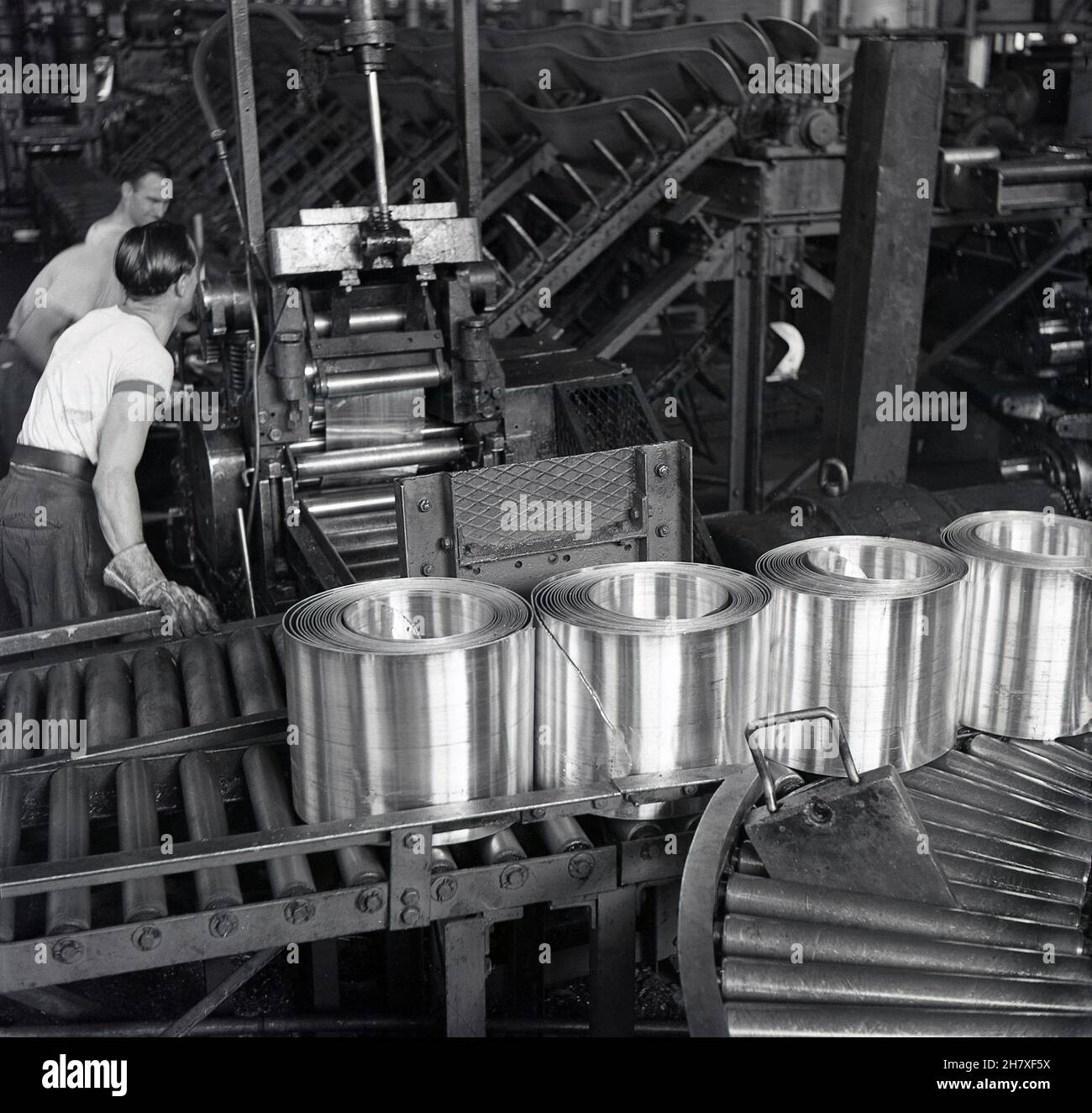 Anni '50, storici, lavoratori maschi presso la fabbrica della società di produzione di batterie, sempre pronti presso i loro impianti a Forest Row, Londra, Inghilterra, Regno Unito, con rotoli di acciaio pressato utilizzati per l'involucro su batterie zinco-carbonio. Foto Stock