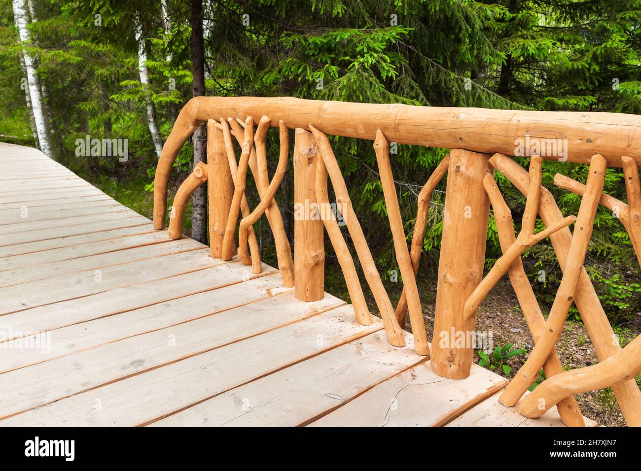 Ringhiere in legno naturale non colorato di una passerella vuota in un parco estivo di giorno Foto Stock