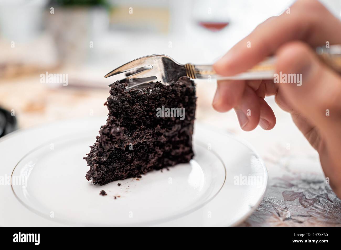 Primo piano macro di forchetta taglio francese scuro morte da cioccolato strato di torta scura su piastra bianca con grana glassa di cacao Foto Stock
