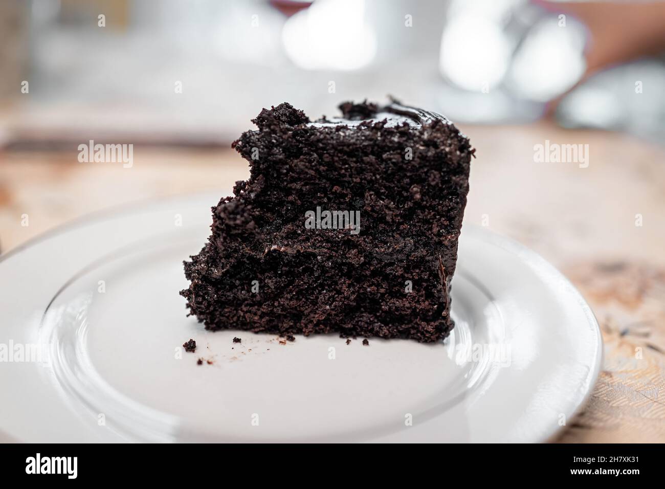 Primo piano macro di morte scura con torta scura a strati di cioccolato un pezzo di fetta su piastra bianca con grana glassa di cacao Foto Stock
