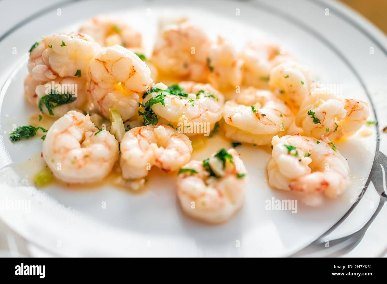 Macrofumo di gamberetti argentini fritti interi cotti con burro all'aglio e prezzemolo alle erbe su piatto bianco che serve la cena Foto Stock