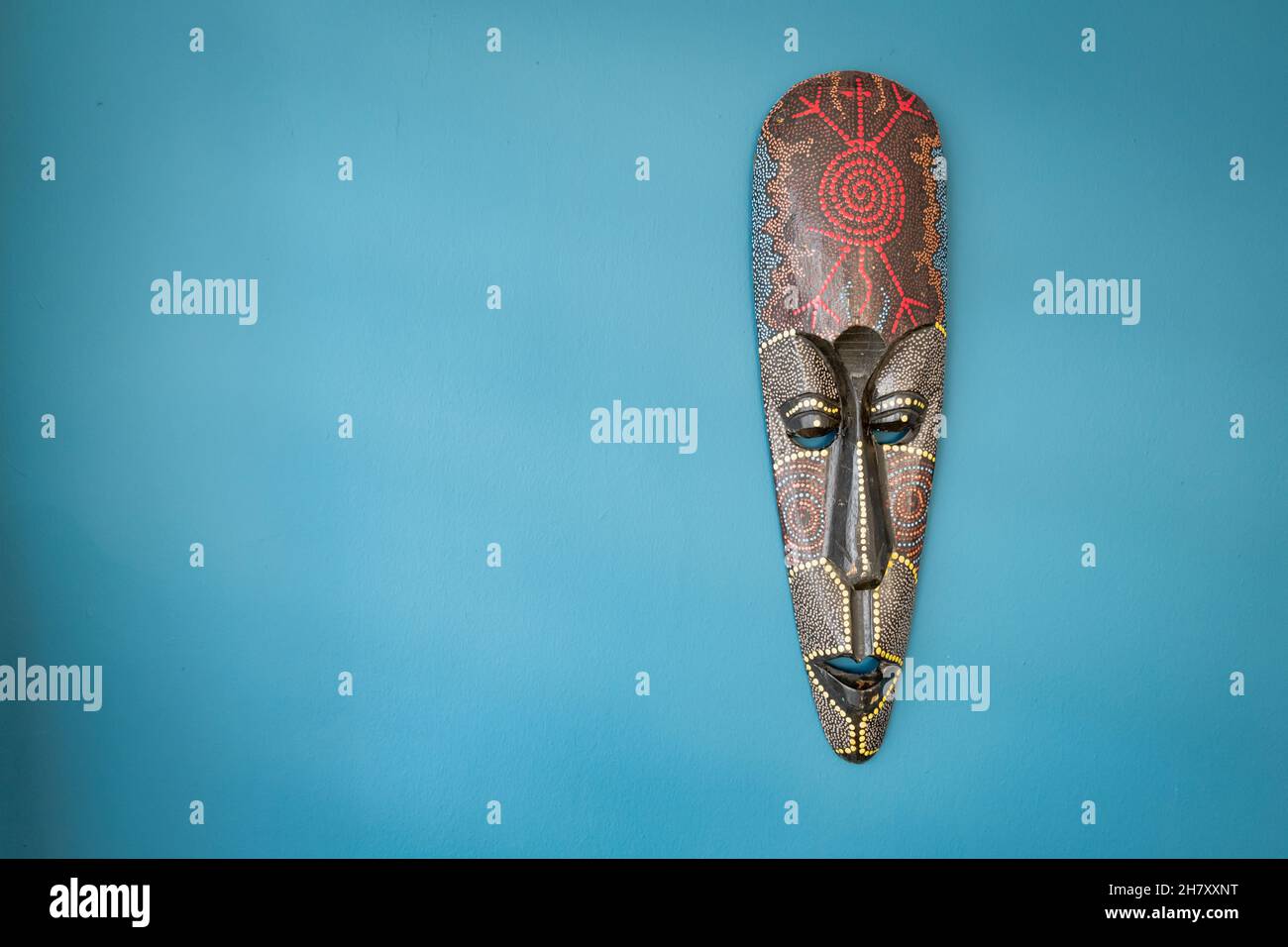 Maschera tribù sul muro. Maschera tribale Africana, maschera nera in legno delle popolazioni indigene Foto Stock