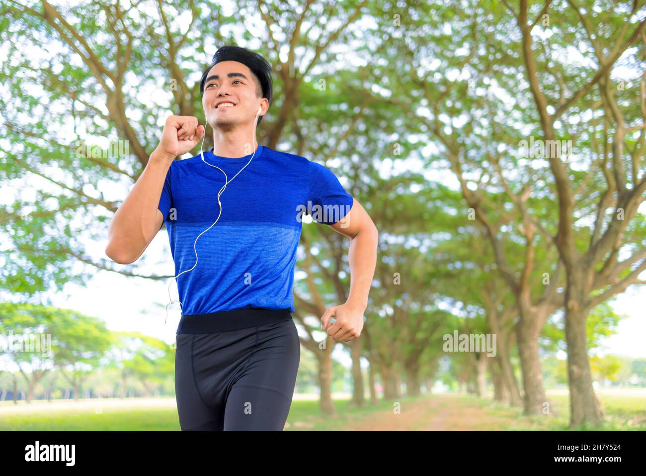 Buon giovane uomo che fa jogging nel parco della città Foto Stock