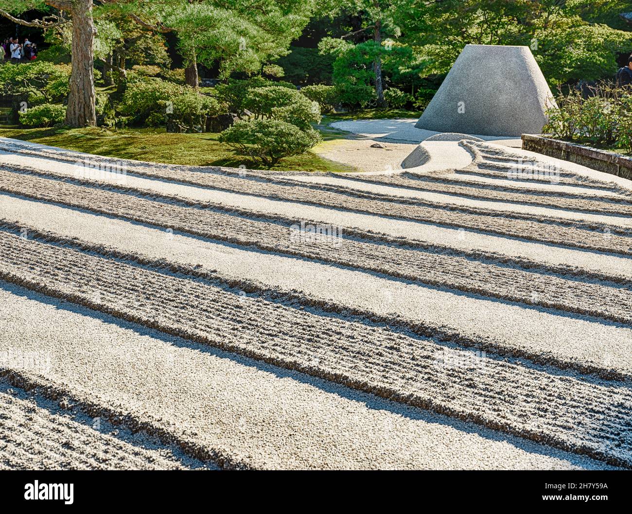 In un giardino Zen, le linee di sabbia rastrellate rappresentano il cielo e le nuvole di fronte ad un cono cilindrico che rappresenta una montagna. Foto Stock