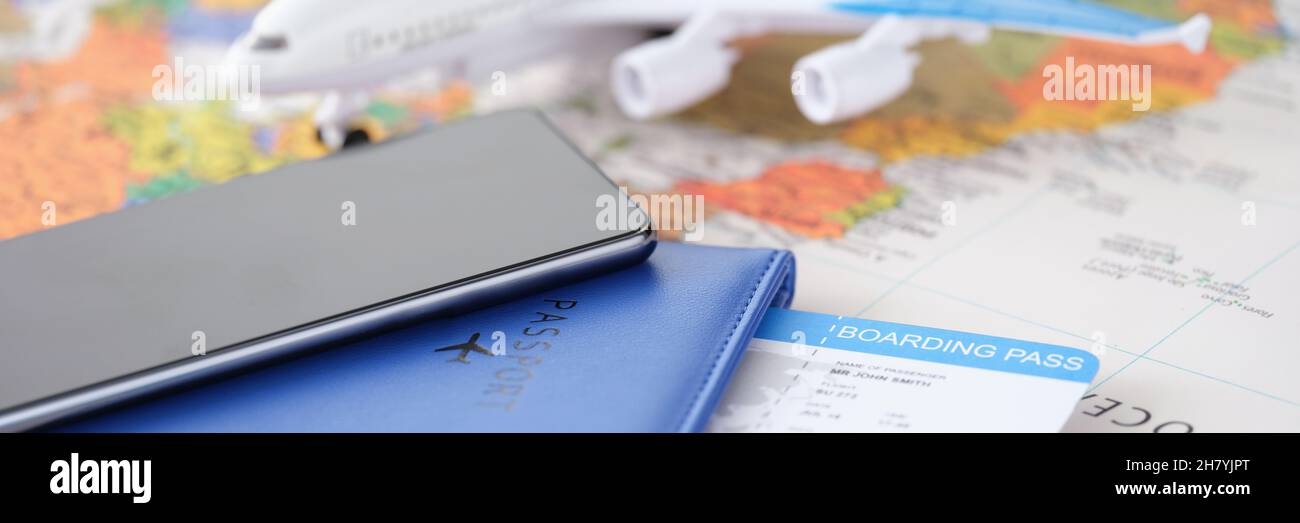 Smartphone con passaporto e biglietti e un aereo si trovano sulla mappa geografica closeup Foto Stock