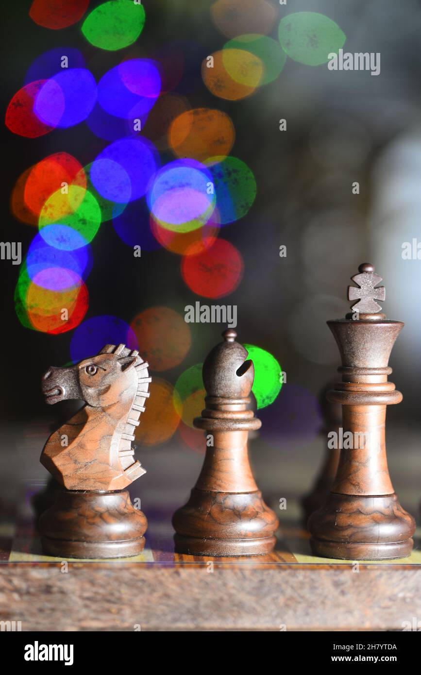 Cavaliere, vescovo e re sulla scacchiera, luci colorate sullo sfondo Foto Stock