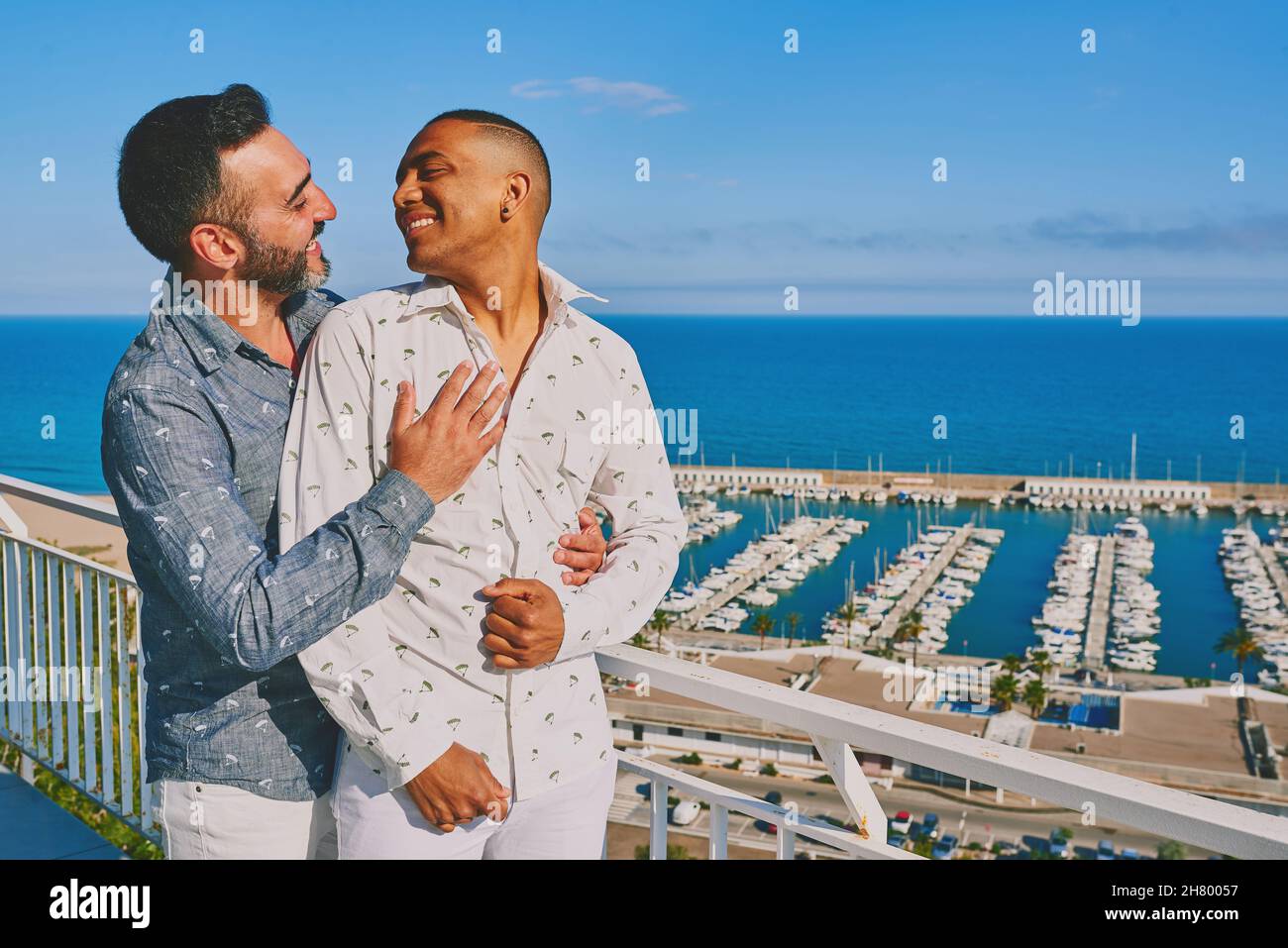 una coppia gay in una giornata estiva soleggiata con il mare alle loro spalle Foto Stock