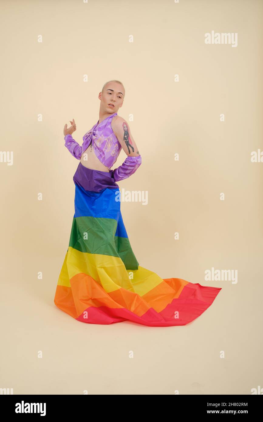 Persona non binaria con bandiera arcobaleno del movimento sociale lgbtq mentre si posa su uno sfondo isolato. Foto Stock