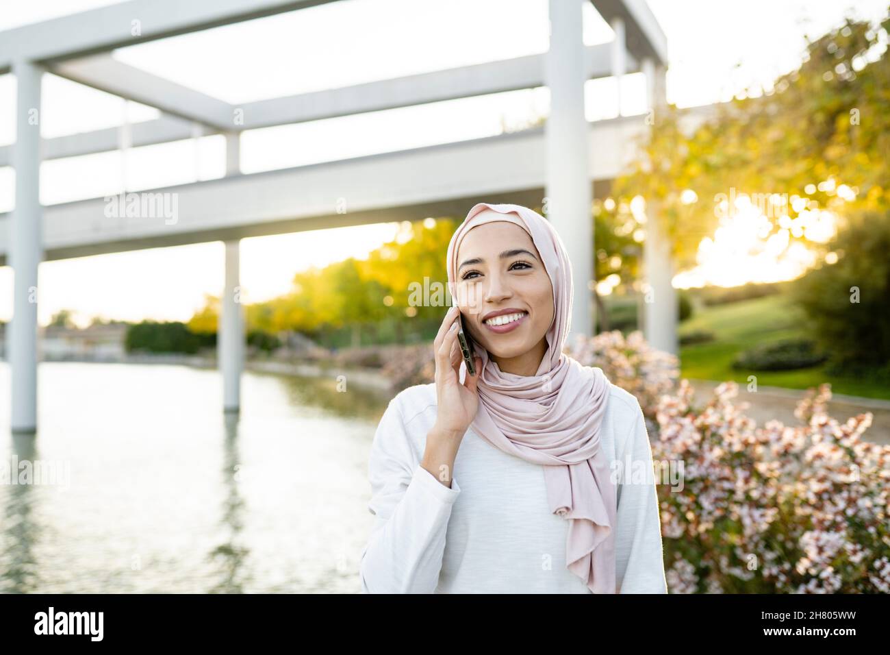 Positiva femmina araba in hijab chiamata dal cellulare dopo l'allenamento di fitness all'aperto Foto Stock