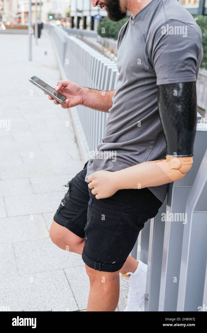 Vista laterale di un modello femminile etnico sicuro in un abito futuristico e occhiali VR a specchio su sfondo turchese illuminati Foto Stock