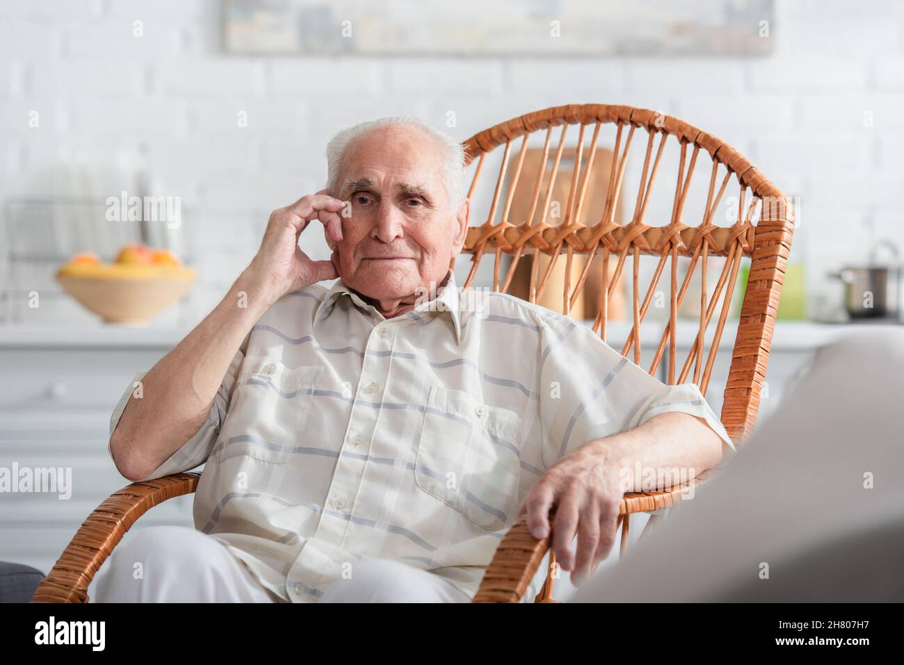 Uomo anziano seduto in sedia a dondolo in casa di cura Foto Stock