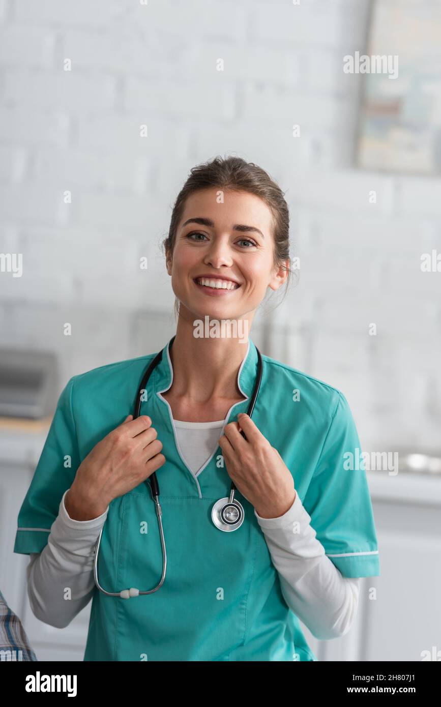 Infermiera sorridente in stetoscopio di tenuta uniforme in casa di cura Foto Stock