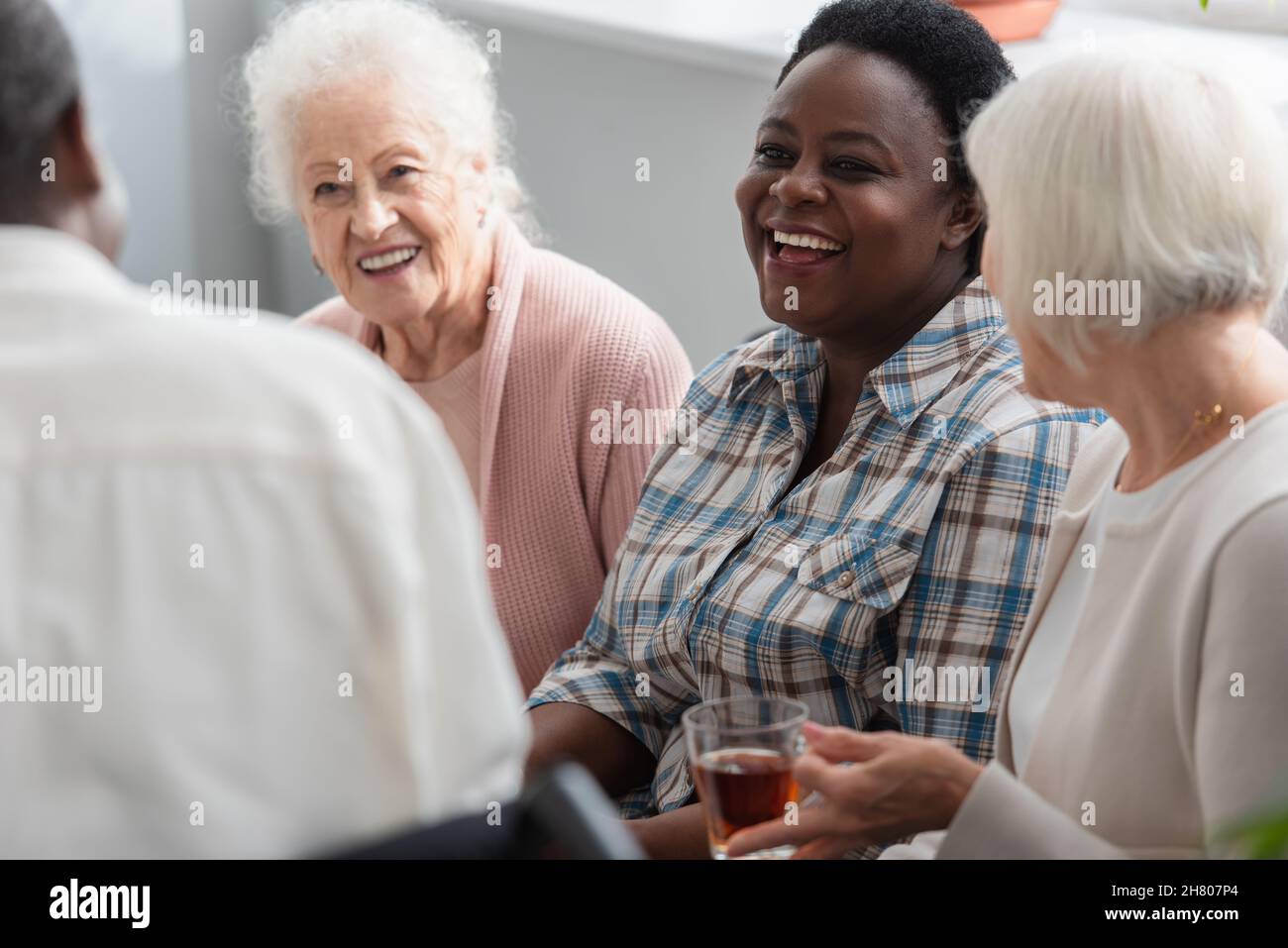 Allegro gente anziana interrazziale con il tè che parla in casa di cura Foto Stock