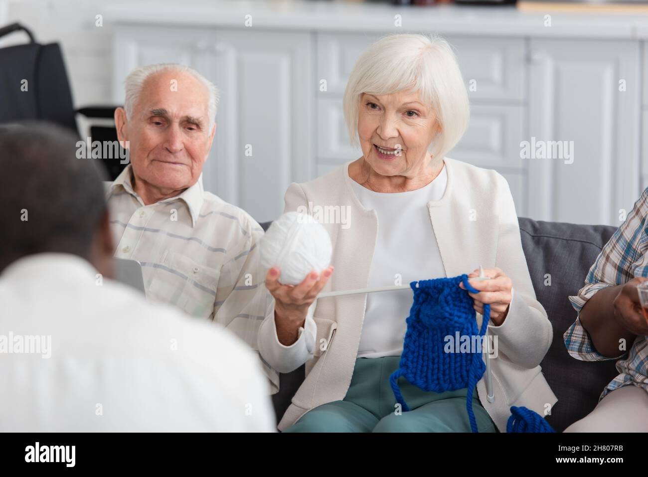 Donna anziana che tiene il filo vicino agli amici interrazziali nella casa di cura Foto Stock