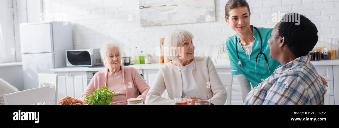 Allegro anziano donne interrazziali parlare con l'infermiera in casa di cura, banner Foto Stock