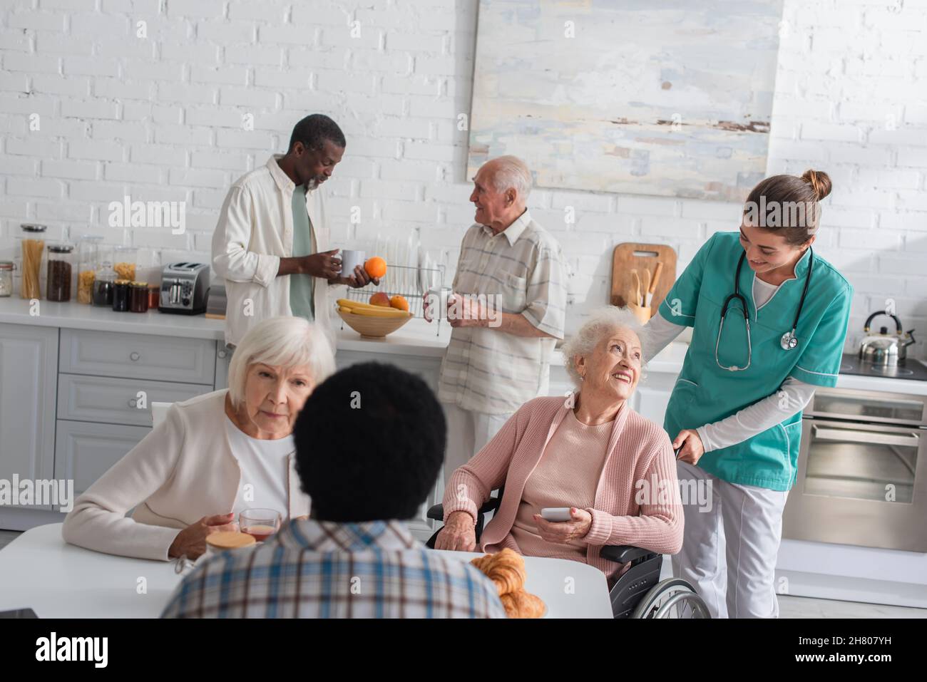Anziani multietnici che trascorrono del tempo con l'infermiera in casa di cura Foto Stock