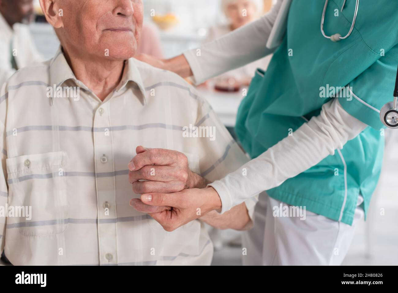 Vista ritagliata dell'infermiere che tiene la mano del paziente anziano in una casa di cura Foto Stock