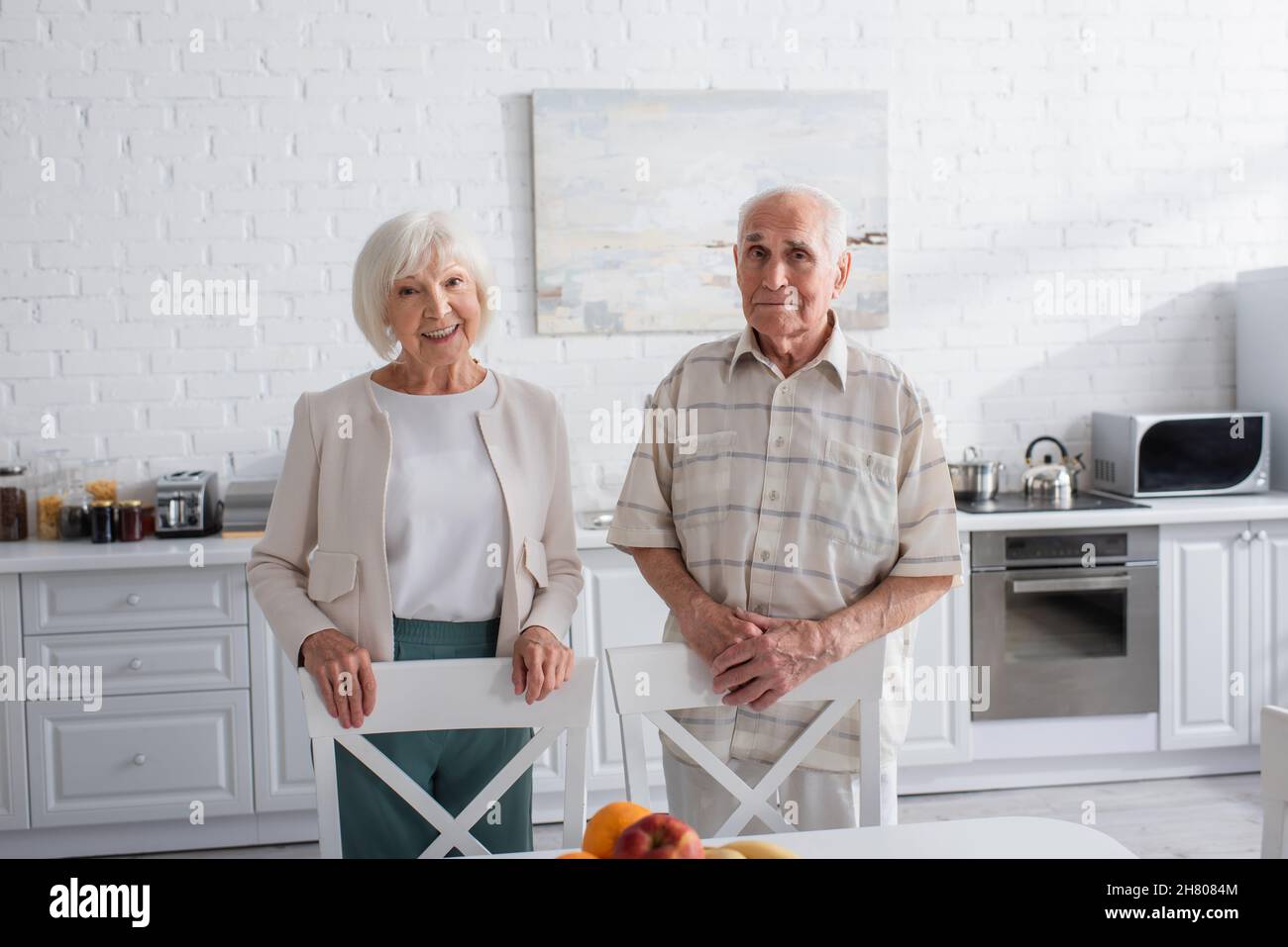 Sorridendo persone anziane che guardano la macchina fotografica in cucina della casa di cura Foto Stock