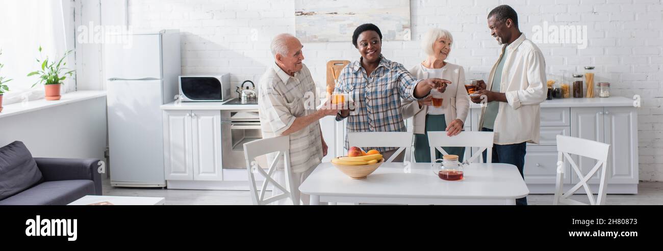 Persone anziane interrazziali positive con tè e smartphone in casa di cura, banner Foto Stock
